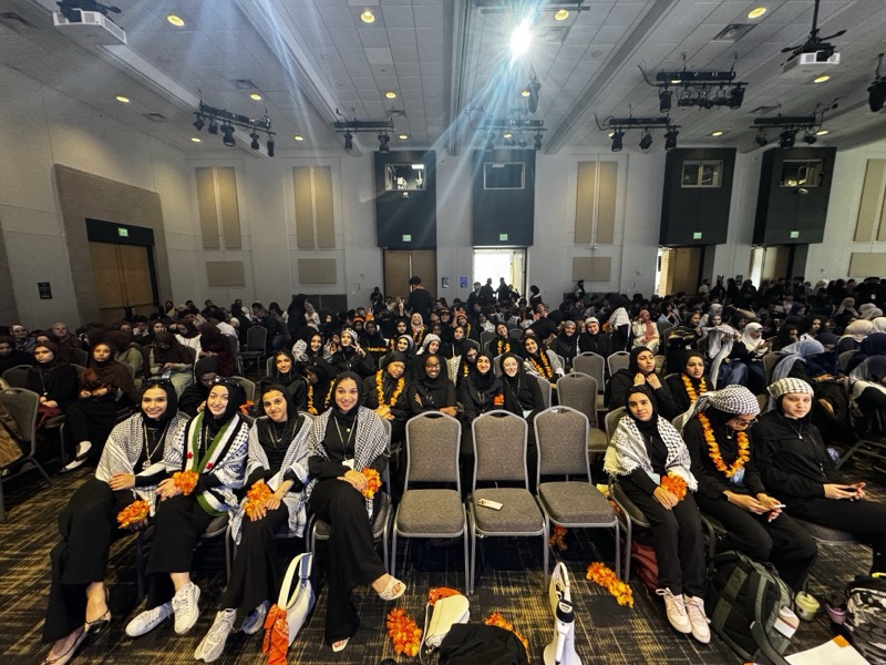 Team seated in auditorium with leis